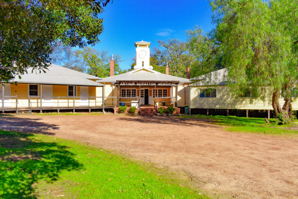 Front view of Arthur Scratton Memorial Building surrounded by trees, featuring its rooftop clock tower at Fairbridge Village