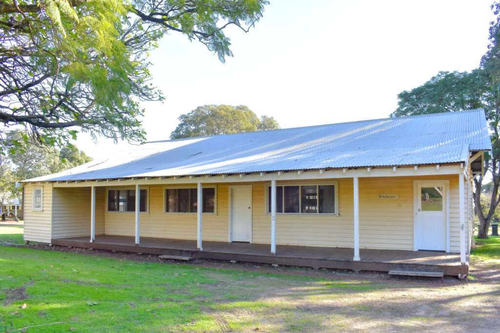 Front view of a small structure Kitchener Cottage with a white roof and a welcoming porch at Fairbridge Village