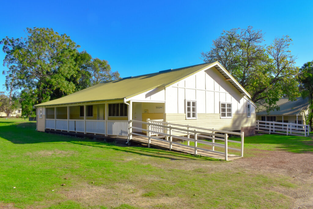 Side view of yellow Livingstone Cottage surrounded by tall trees, the best southwest accommodation at Fairbridge Village