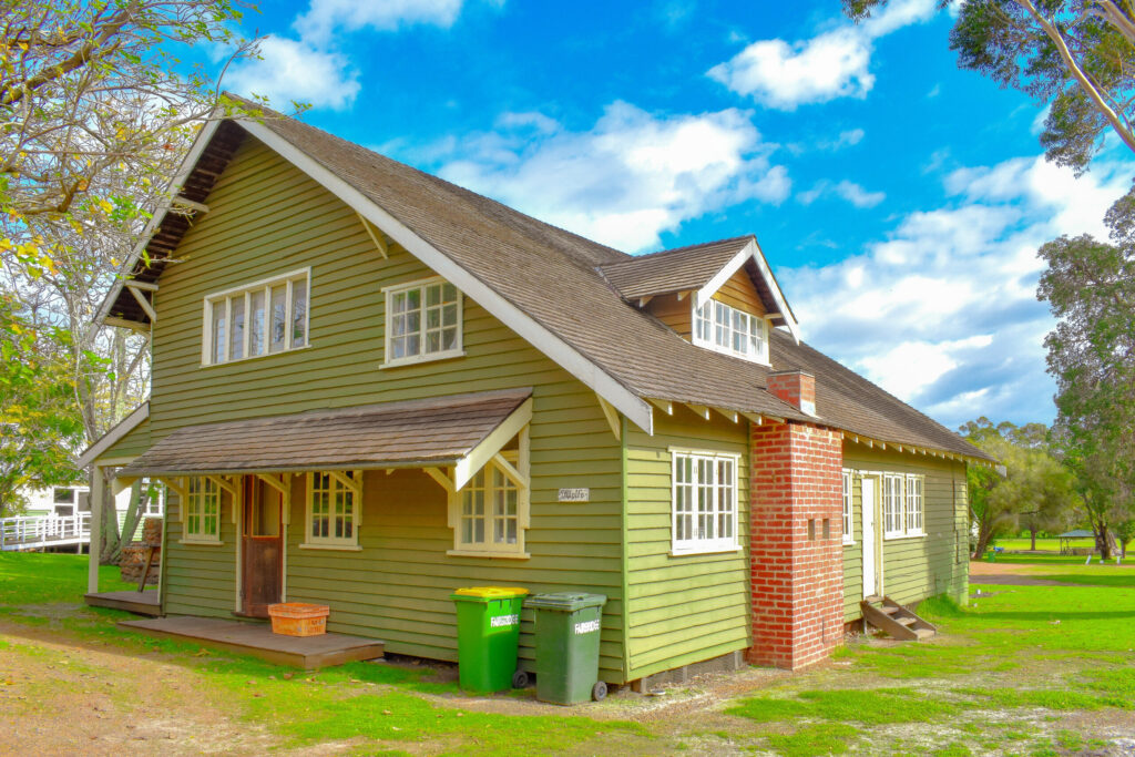Close-up view of Green Wolfe Cottage surrounded by trees located in south west accommodation area at Fairbridge Village