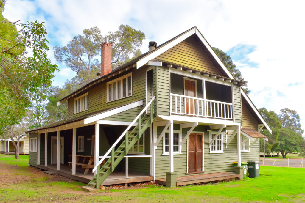 Side view of large green Middlemore Cottage with a porch and balcony nestled at Fairbridge Village