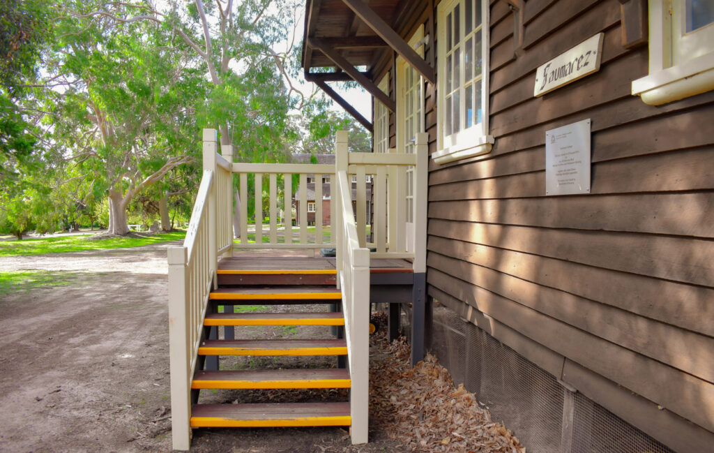 Wooden staircase ascending to Saumarez Cottage with a porch in south west accommodation at Fairbridge Village