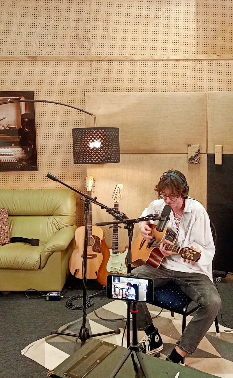 A man in white polo playing guitar in a music studio located in Fairbridge Village