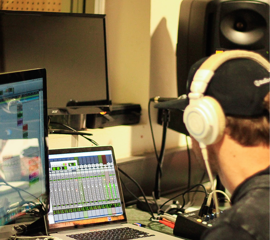 Man wearing headphones is focused on his computer in a music studio located in Fairbridge Village
