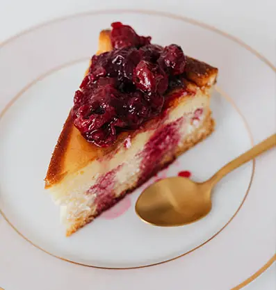 Delicious cranberry cheesecake on a plate with a golden spoon beside it, beautifully presented at Fairbridge Village